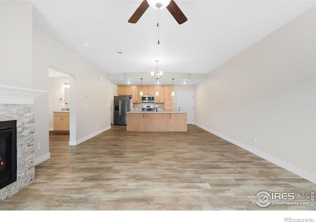 4672 Hahns Peak Dr Unit 101, Loveland, CO 80538 - kitchen with appliances with stainless steel finishes, open floor plan, a fireplace, a ceiling fan, and tasteful backsplash