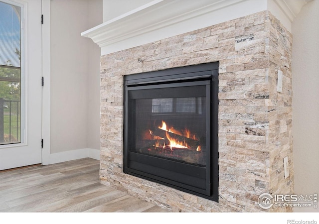 4672 Hahns Peak Dr Unit 101, Loveland, CO 80538 - detailed view of a glass covered fireplace, wood finished floors, and baseboards