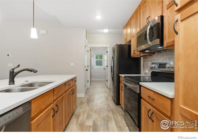 4672 Hahns Peak Dr Unit 101, Loveland, CO 80538 - kitchen with appliances with stainless steel finishes, a sink, light wood-type flooring, decorative backsplash, and light countertops