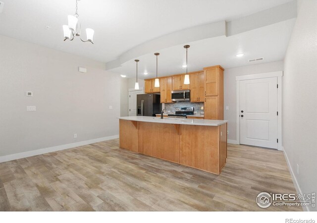 4672 Hahns Peak Dr Unit 101, Loveland, CO 80538 - kitchen featuring appliances with stainless steel finishes, light countertops, tasteful backsplash, a chandelier, and light wood-style floors