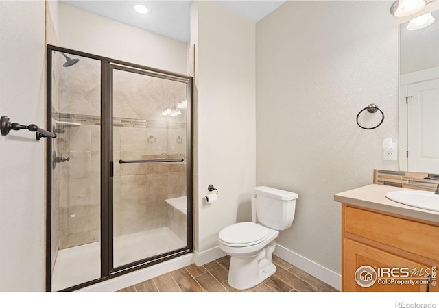 4672 Hahns Peak Dr Unit 101, Loveland, CO 80538 - bathroom featuring toilet, vanity, wood tiled floors, a stall shower, and baseboards