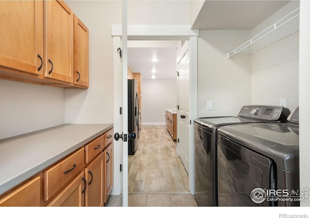 4672 Hahns Peak Dr Unit 101, Loveland, CO 80538 - laundry area featuring washer and clothes dryer, cabinet space, and light wood-style flooring