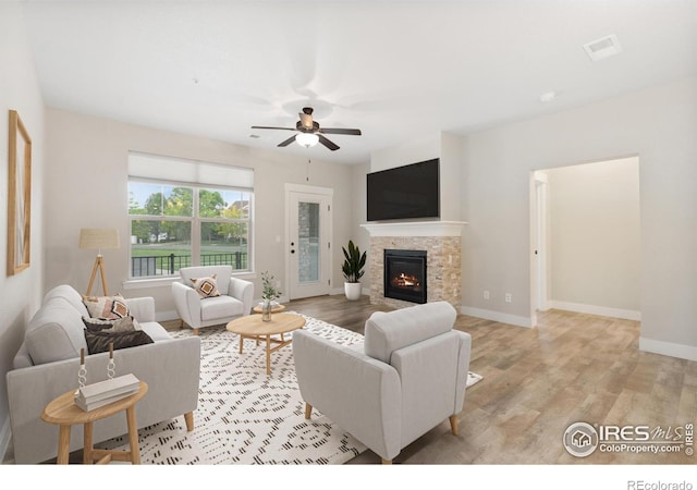 4672 Hahns Peak Dr Unit 101, Loveland, CO 80538 - living area with a ceiling fan, light wood-style floors, a fireplace, and baseboards