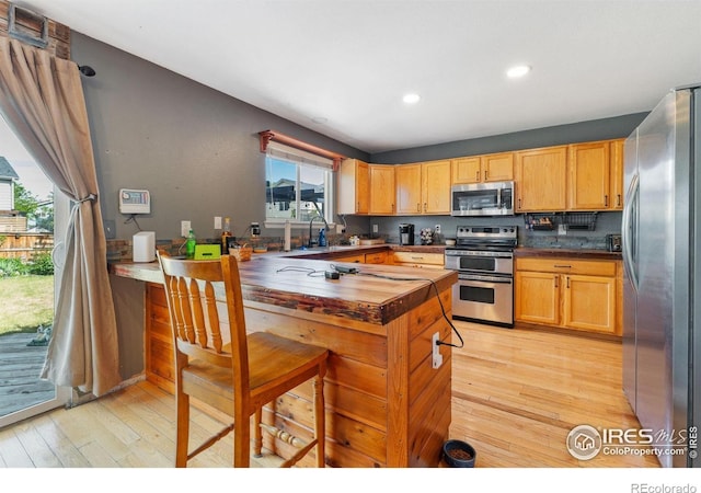 1086 Mockingbird St, Brighton, CO 80601 - kitchen featuring appliances with stainless steel finishes, light wood-style flooring, a peninsula, recessed lighting, and wood counters