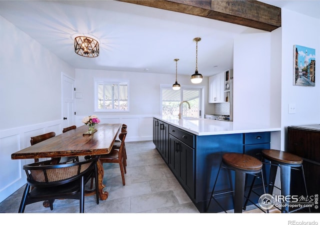 855 33rd St, Boulder, CO 80303 - kitchen featuring light countertops, a sink, a wainscoted wall, decorative light fixtures, and a breakfast bar area