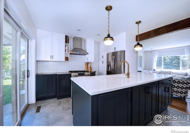 855 33rd St, Boulder, CO 80303 - kitchen featuring wall chimney exhaust hood, appliances with stainless steel finishes, open floor plan, white cabinets, and decorative backsplash