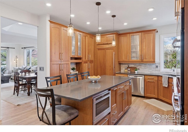 4094 Bimini Ct, Boulder, CO 80301 - kitchen featuring appliances with stainless steel finishes, dark countertops, a kitchen breakfast bar, light wood finished floors, and decorative backsplash