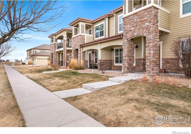 5020 Cinquefoil Ln Unit E, Fort Collins, CO 80528 - view of front of house featuring stone siding, covered porch, a balcony, and a front lawn