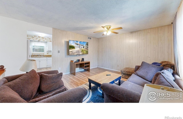 8208 Peakview Dr, Fort Collins, CO 80528 - living room with wood finished floors, ceiling fan, baseboards, a textured ceiling, and wood walls