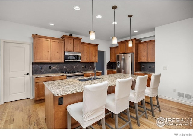 873 Signal Ct, Timnath, CO 80547 - kitchen with appliances with stainless steel finishes, a sink, brown cabinets, an island with sink, and recessed lighting