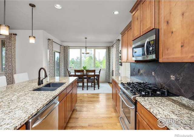 873 Signal Ct, Timnath, CO 80547 - kitchen featuring appliances with stainless steel finishes, a sink, light wood-style flooring, brown cabinets, and recessed lighting