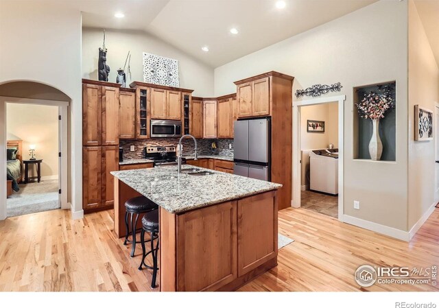 405 Timber Ridge Parkway, Severance, CO 80550 - kitchen with appliances with stainless steel finishes, a sink, arched walkways, separate washer and dryer, and high vaulted ceiling