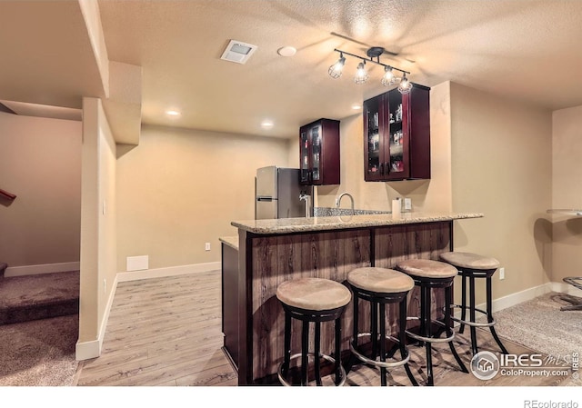 405 Timber Ridge Parkway, Severance, CO 80550 - indoor wet bar with freestanding refrigerator, a textured ceiling, baseboards, and light wood-style flooring