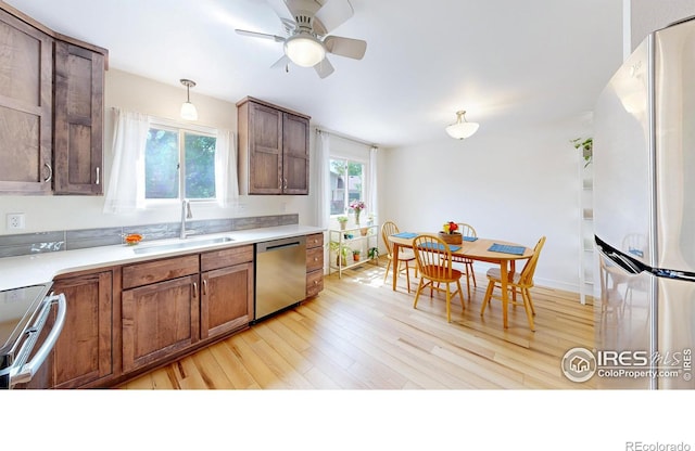 2415 Sunray Ct, Fort Collins, CO 80525 - kitchen featuring stainless steel appliances, light wood finished floors, a sink, ceiling fan, and light countertops