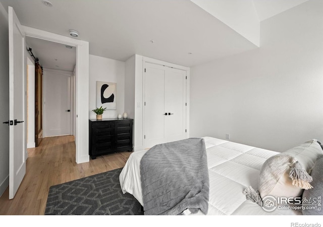 2434 Mapleton Ave, Boulder, CO 80304 - bedroom with light wood-style flooring, baseboards, a barn door, and a closet