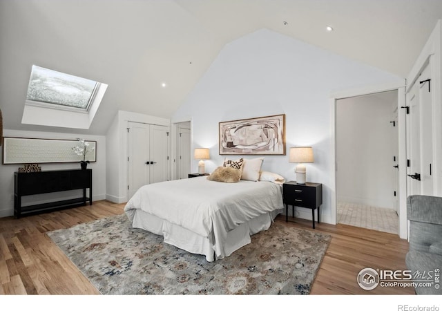 2434 Mapleton Ave, Boulder, CO 80304 - bedroom featuring a skylight, wood finished floors, high vaulted ceiling, and two closets