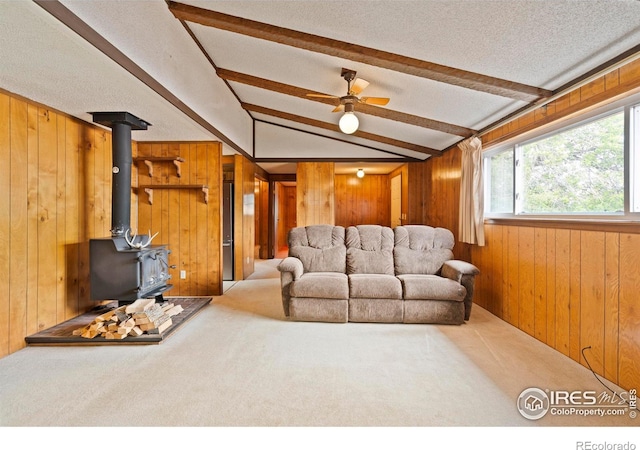 1155 Caroline Ct, Loveland, CO 80537 - living room featuring wooden walls, a wood stove, carpet, ceiling fan, and a textured ceiling