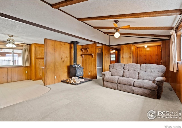 1155 Caroline Ct, Loveland, CO 80537 - carpeted living area featuring wood walls, a ceiling fan, a wood stove, and a textured ceiling