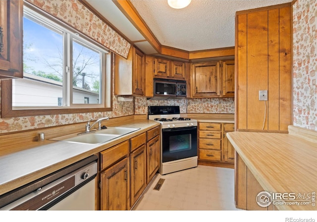 1155 Caroline Ct, Loveland, CO 80537 - kitchen with black microwave, white gas stove, dishwasher, a sink, and light countertops