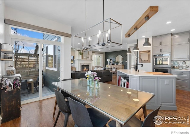 6434 Cloudburst Ave, Timnath, CO 80547 - dining space with dark wood-style floors, a lit fireplace, a chandelier, and recessed lighting