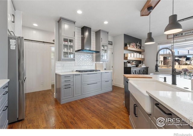 6434 Cloudburst Ave, Timnath, CO 80547 - kitchen featuring wall chimney range hood, gray cabinetry, appliances with stainless steel finishes, a sink, and dark wood-style floors