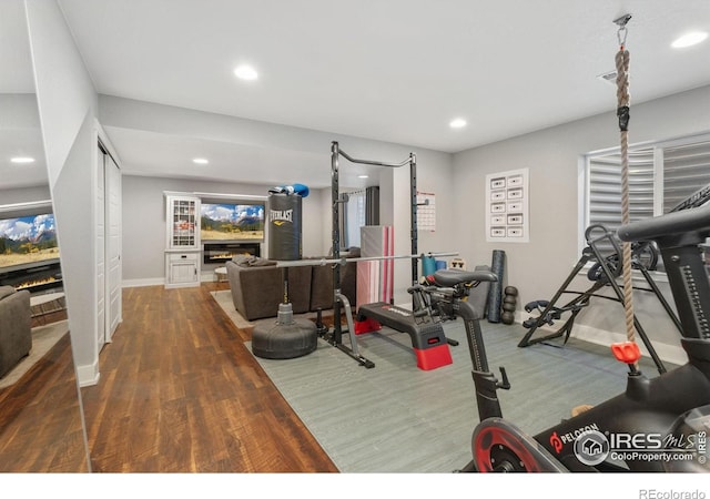 6434 Cloudburst Ave, Timnath, CO 80547 - exercise room featuring a glass covered fireplace, recessed lighting, baseboards, and wood finished floors