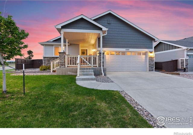 5309 Maher Ave, Loveland, CO 80538 - view of front of house with stone siding, an attached garage, driveway, and a porch