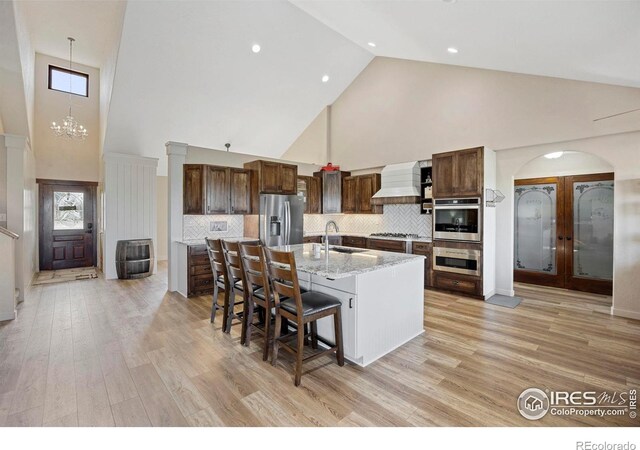33820 County Road 47, Greeley, CO 80631 - kitchen featuring stainless steel appliances, high vaulted ceiling, premium range hood, a sink, and a kitchen bar