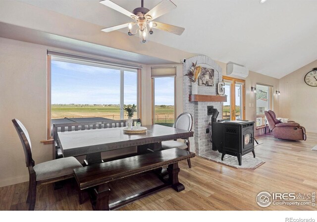 33820 County Road 47, Greeley, CO 80631 - dining space featuring a wood stove, wood finished floors, a wall unit AC, lofted ceiling, and ceiling fan