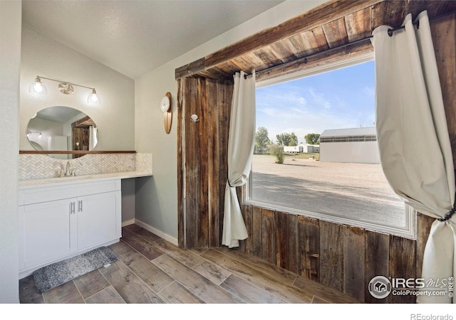 33820 County Road 47, Greeley, CO 80631 - bathroom with decorative backsplash, vanity, wood finished floors, and lofted ceiling