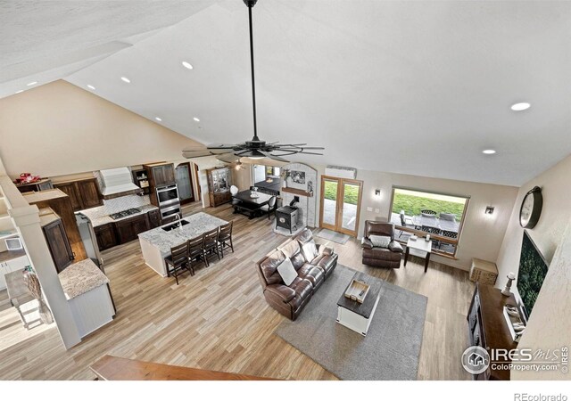 33820 County Road 47, Greeley, CO 80631 - living room featuring vaulted ceiling, light wood-style floors, ceiling fan, recessed lighting, and a fireplace