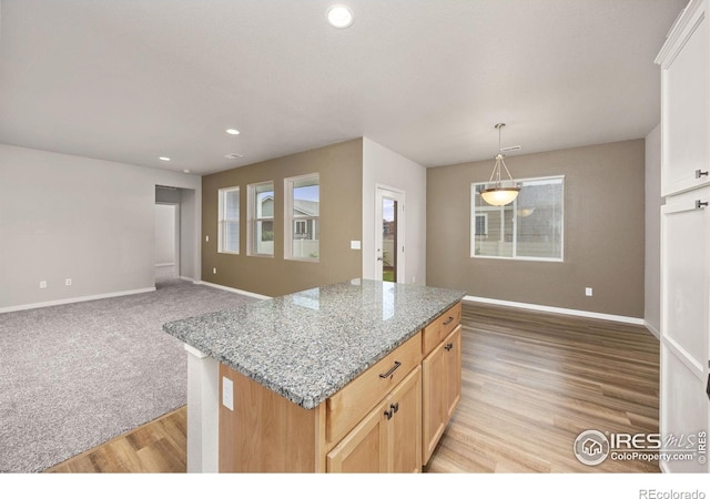 3925 Buckthorn St, Wellington, CO 80549 - kitchen with baseboards, recessed lighting, a center island, light wood finished floors, and light stone countertops
