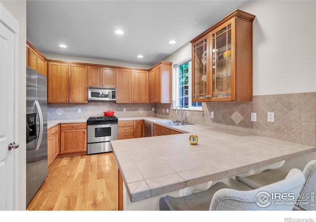 13255 Red Deer Trl, Broomfield, CO 80020 - kitchen featuring appliances with stainless steel finishes, a sink, a peninsula, light wood-style flooring, and a breakfast bar