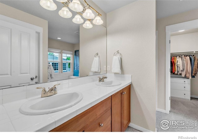 13255 Red Deer Trl, Broomfield, CO 80020 - full bathroom featuring double vanity, a chandelier, baseboards, and a walk in closet