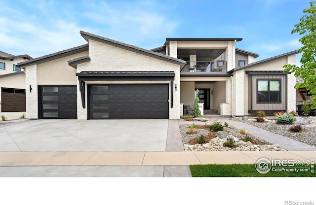 2712 Bluewater Rd, Berthoud, CO 80513 - modern home with a balcony, an attached garage, concrete driveway, and stucco siding