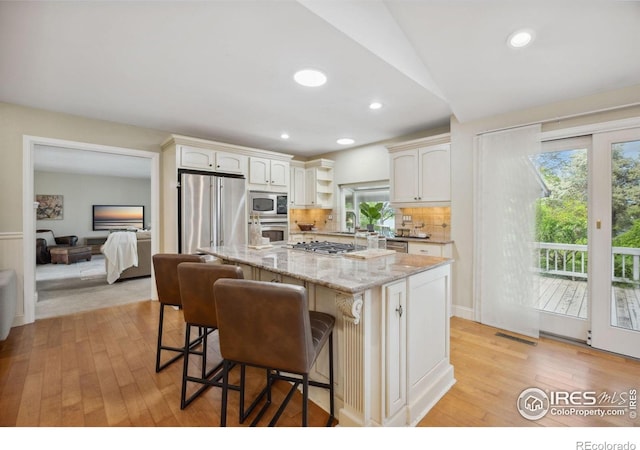 1400 38th Ave, Greeley, CO 80634 - kitchen featuring stainless steel appliances, light wood finished floors, light stone counters, a center island, and a kitchen breakfast bar