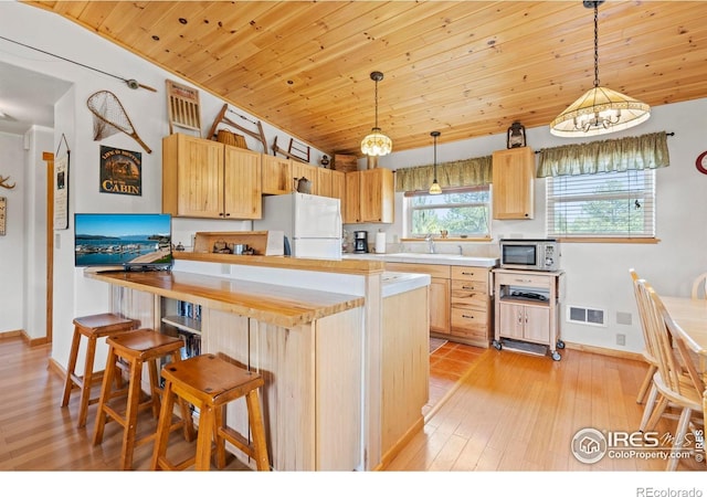 251 Huron Rd, Red Feather Lakes, CO 80545 - kitchen featuring freestanding refrigerator, stainless steel microwave, light brown cabinets, a kitchen bar, and baseboards