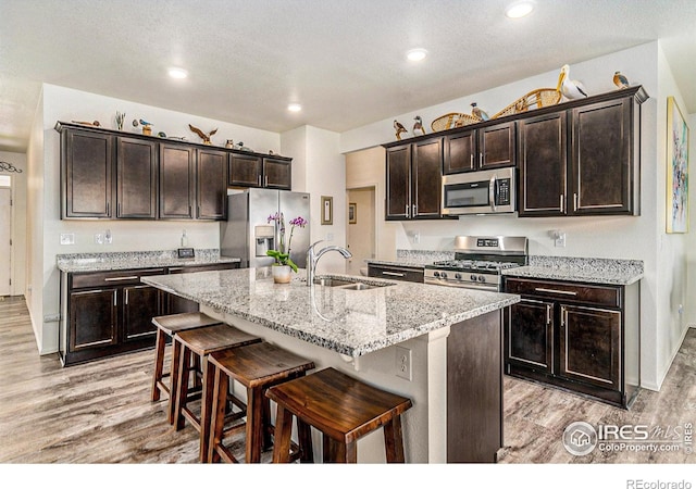 926 Birchdale Ct, Windsor, CO 80550 - kitchen featuring appliances with stainless steel finishes, a sink, light wood-type flooring, a kitchen breakfast bar, and recessed lighting