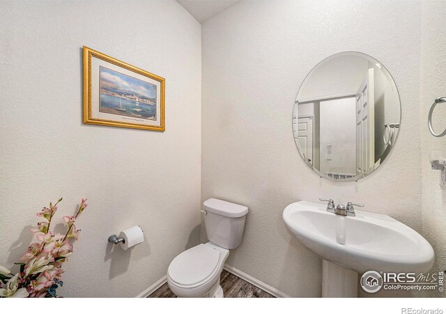 926 Birchdale Ct, Windsor, CO 80550 - half bathroom with wood finished floors, toilet, a sink, and baseboards