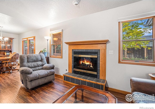 209 N 44th Avenue Ct, Greeley, CO 80634 - living area featuring wood finished floors, baseboards, a textured ceiling, and a tiled fireplace