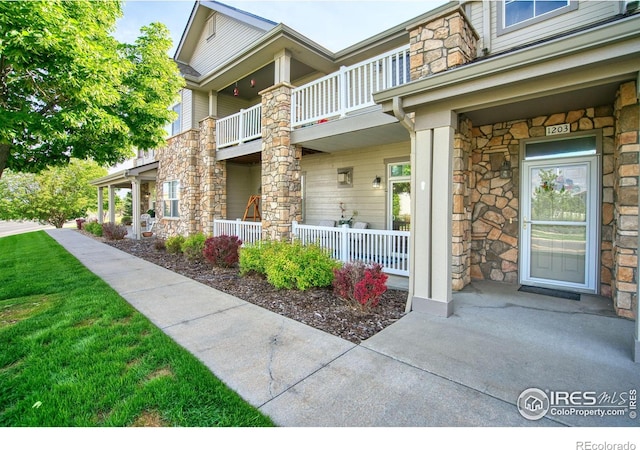 10818 Cimarron St Unit 1203, Firestone, CO 80504 - property entrance featuring a balcony, stone siding, and covered porch