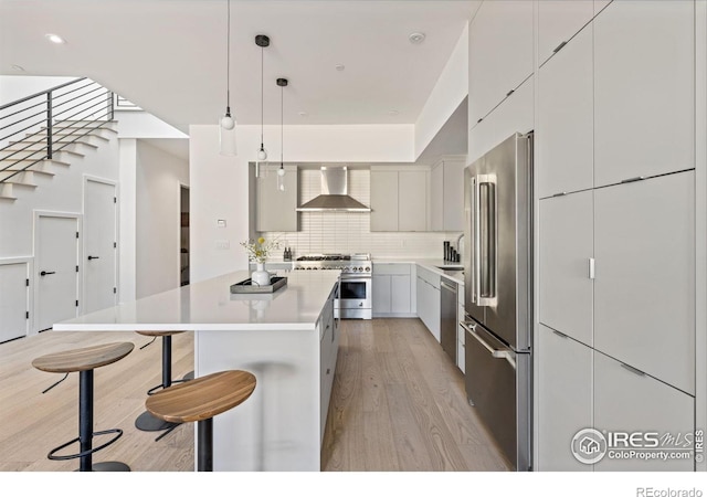 3335 Broadway St, Boulder, CO 80304 - kitchen with modern cabinets, premium appliances, wall chimney range hood, a breakfast bar, and light wood finished floors