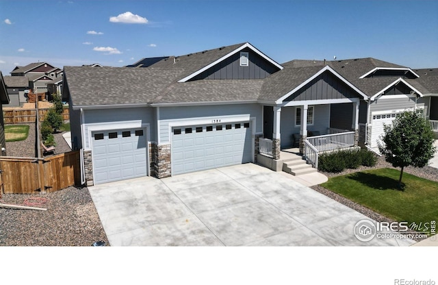 1384 Copeland Falls Rd, Severance, CO 80550 - view of front of home with a garage, board and batten siding, concrete driveway, stone siding, and a porch