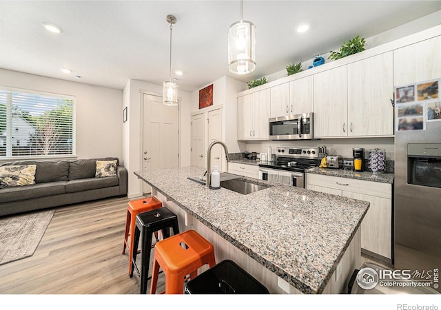 1099 Spartan Ave, Berthoud, CO 80513 - kitchen with stainless steel appliances, a sink, a kitchen bar, light wood finished floors, and recessed lighting