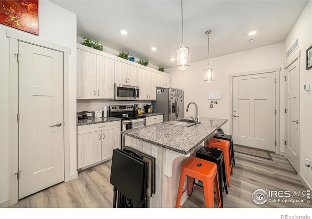 1099 Spartan Ave, Berthoud, CO 80513 - kitchen with appliances with stainless steel finishes, light wood finished floors, a breakfast bar, recessed lighting, and a sink