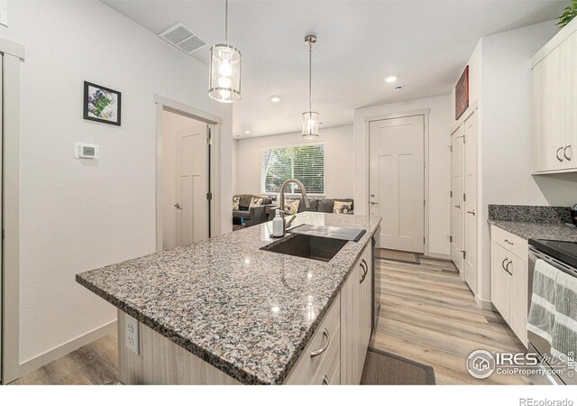 1099 Spartan Ave, Berthoud, CO 80513 - kitchen with stainless steel electric range oven, a sink, light wood-type flooring, a center island with sink, and baseboards