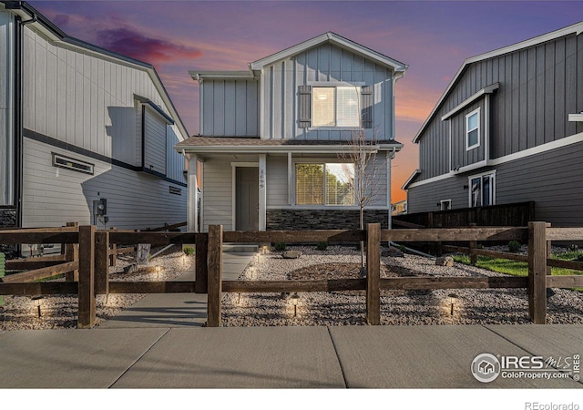 1099 Spartan Ave, Berthoud, CO 80513 - view of front facade featuring board and batten siding, a fenced front yard, a porch, and stone siding