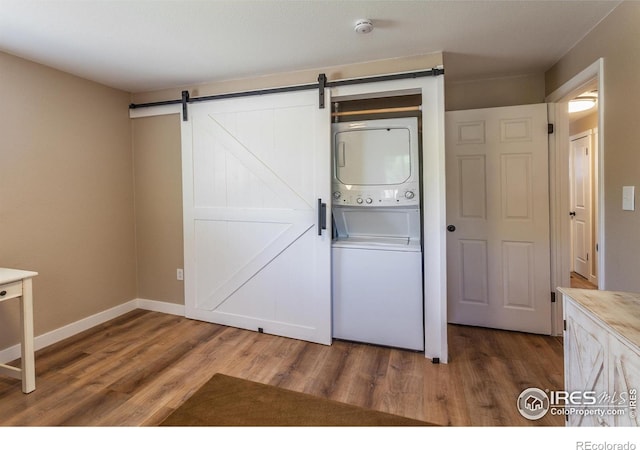 501 Copeland Way, Longmont, CO 80504 - laundry area featuring estacked washer and dryer, wood finished floors, a barn door, and baseboards