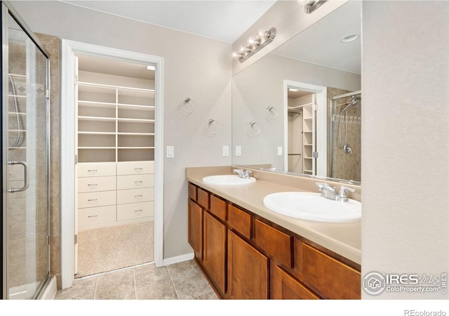 6492 Richland Ave, Timnath, CO 80547 - bathroom featuring a walk in closet, double vanity, a shower stall, and tile patterned flooring