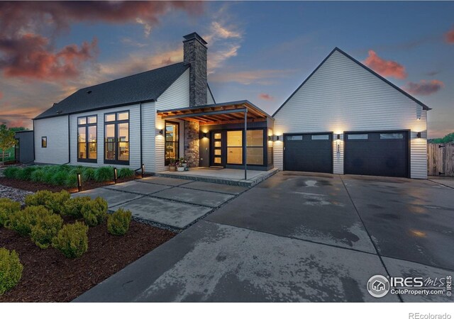 1563 Spring Creek Xing, Lafayette, CO 80026 - back of property at dusk featuring driveway and a chimney